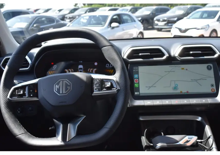 Vue intérieure centrée sur le volant MG et l’écran tactile du tableau de bord du MG ZS blanc hybride 2026.