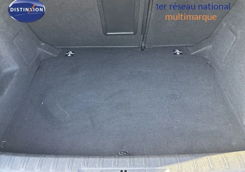 Coffre vide en tissu gris foncé d'une Peugeot 308 blanc nacré, vue de dessus depuis l'ouverture arrière.