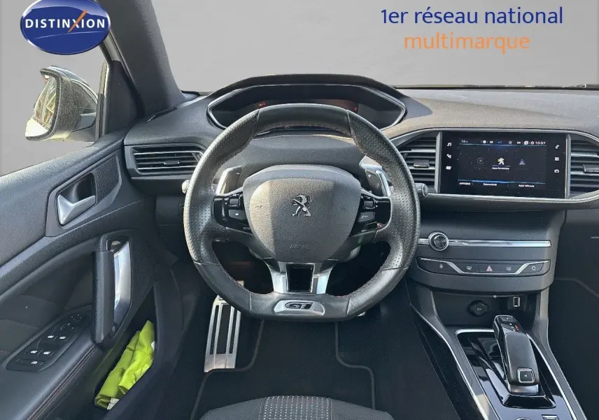 Vue intérieure centrée sur le volant cuir GT et la console centrale de la Peugeot 308 blanche nacrée de 2021.