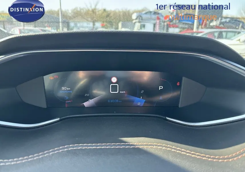 Tableau de bord numérique de Peugeot 308 blanc nacré 2021, affichant vitesse, autonomie et kilométrage.