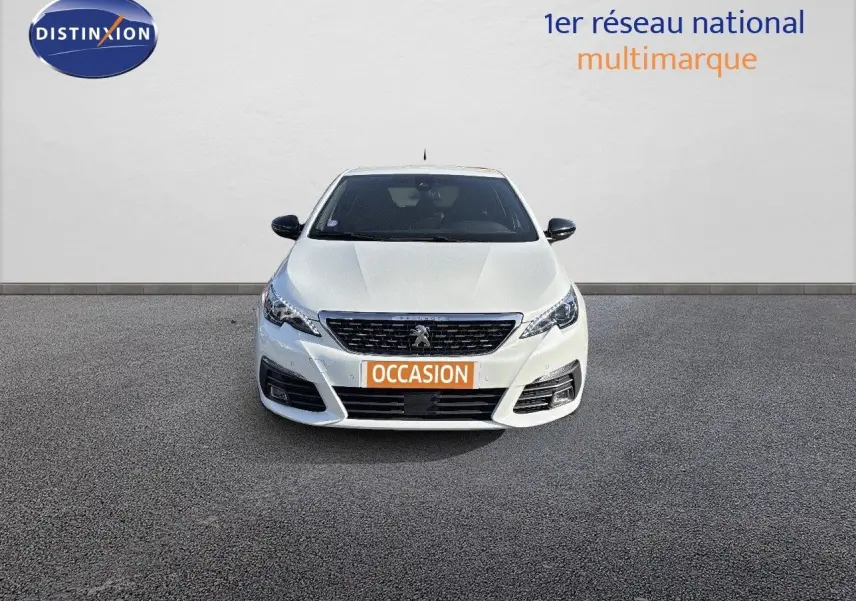 Peugeot 308 blanc nacré vue de face, avec calandre noire et plaque "OCCASION" orange visible.