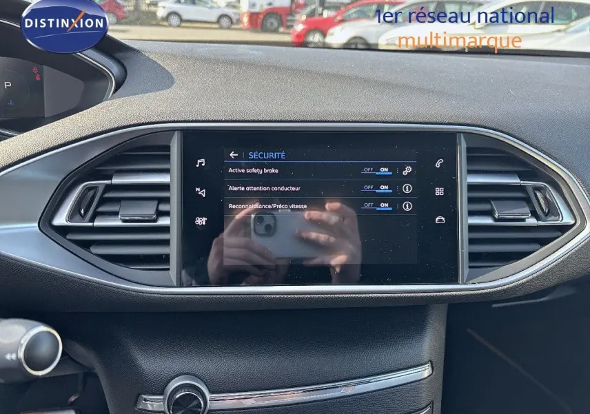 Vue rapprochée de l'écran tactile central et des aérateurs du tableau de bord d'une Peugeot 308 blanc nacré 2021.