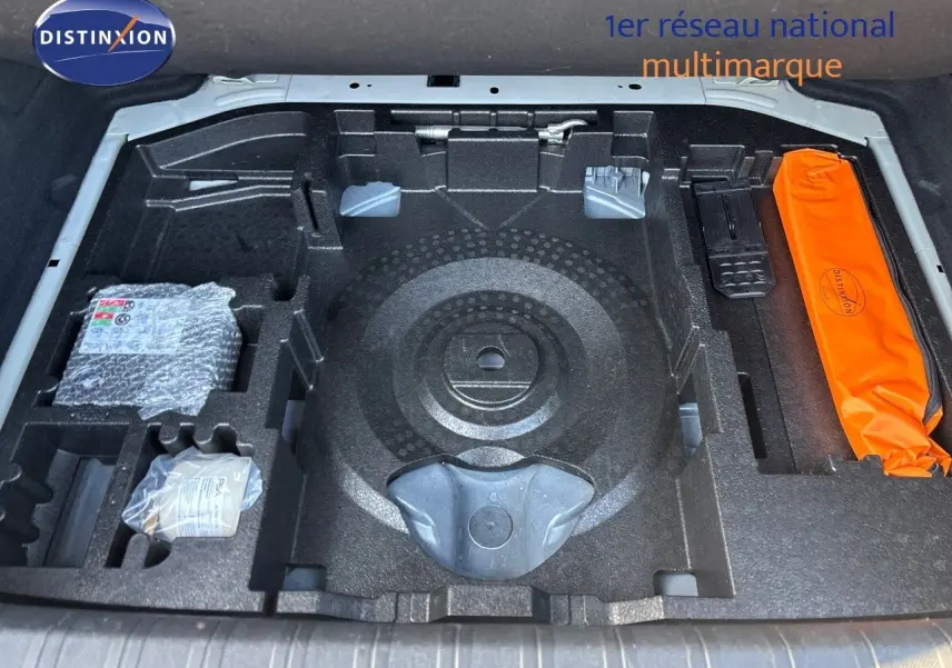 Compartiment de rangement sous le coffre de la Peugeot 308 blanc nacré, montrant les emplacements pour outils et accessoires.