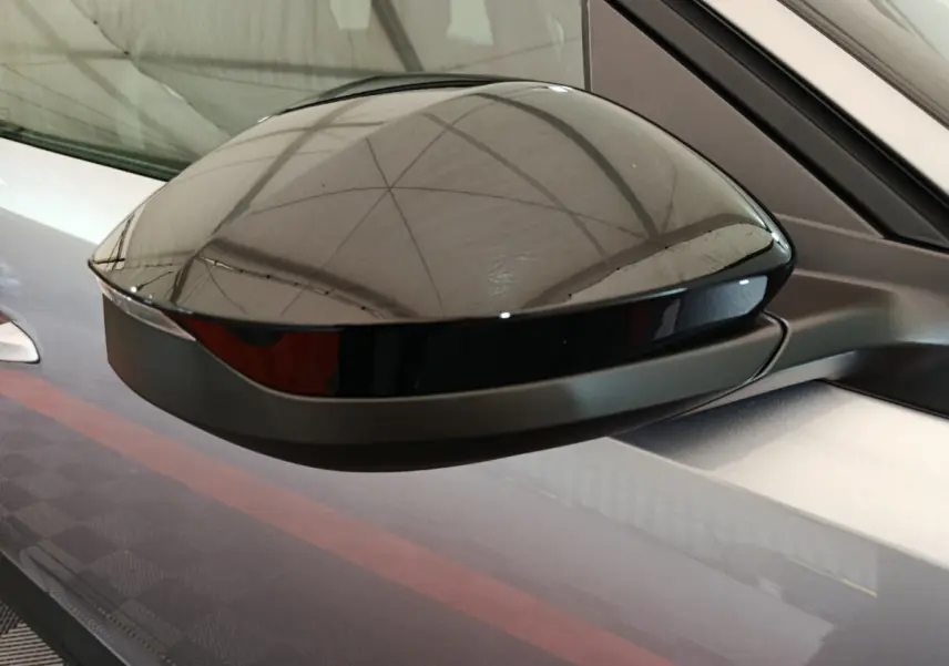 Gros plan sur le rétroviseur droit noir brillant du Peugeot 3008 gris clair hybride 2025, soulignant sa finition moderne.