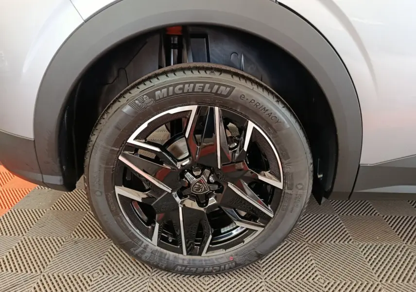 Gros plan sur la roue avant droite du Peugeot 3008 gris clair, jante alliage noir et argent avec logo lion central.
