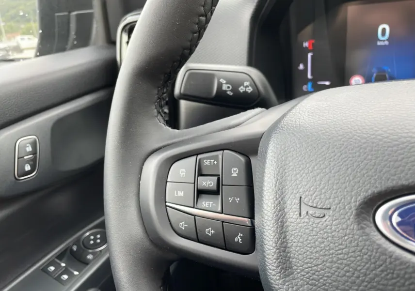 Gros plan sur le volant cuir multifonctions côté gauche du Ford Ranger gris carbone, avec commandes de régulateur et audio.