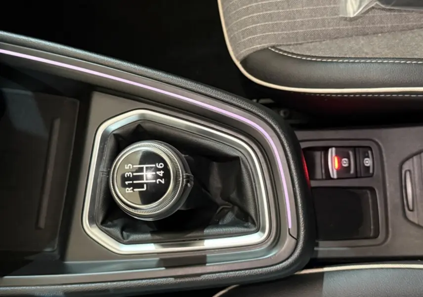 Gros plan sur le levier de vitesses manuel entouré d'un éclairage d'ambiance violet dans la Renault Clio Techno rouge.