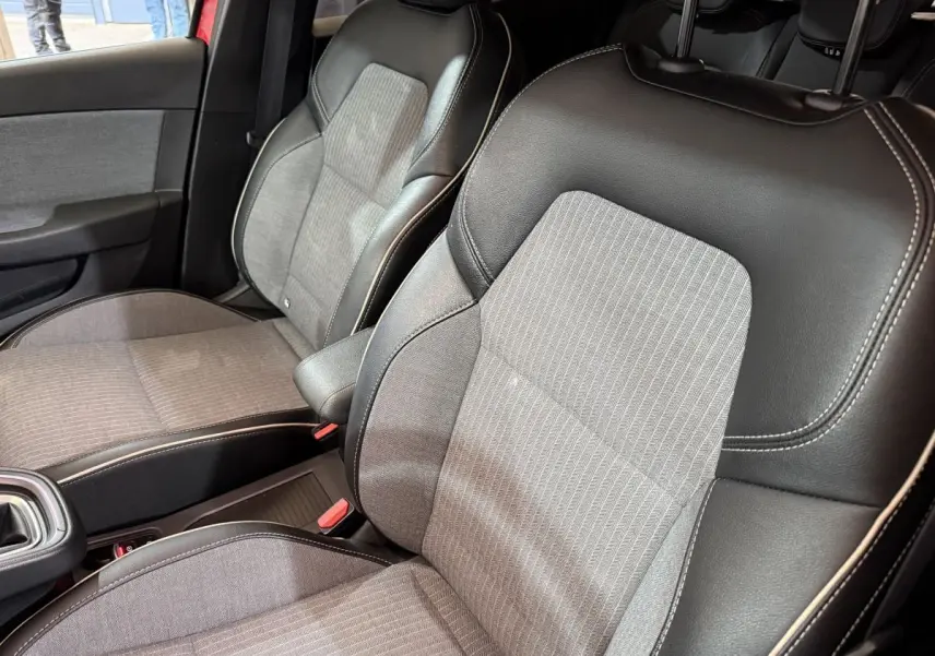 Gros plan sur les sièges avant gris et noirs de la Renault Clio Techno TCe 90 2024 avec surpiqûres blanches.