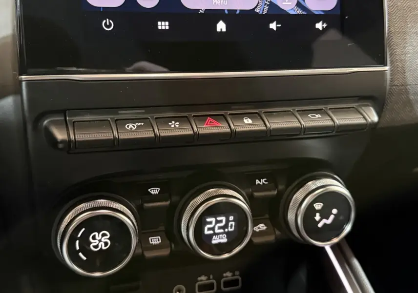 Gros plan sur la console centrale de la Renault Clio Techno TCe 90 2024, montrant les commandes de climatisation et les boutons multifonctions.
