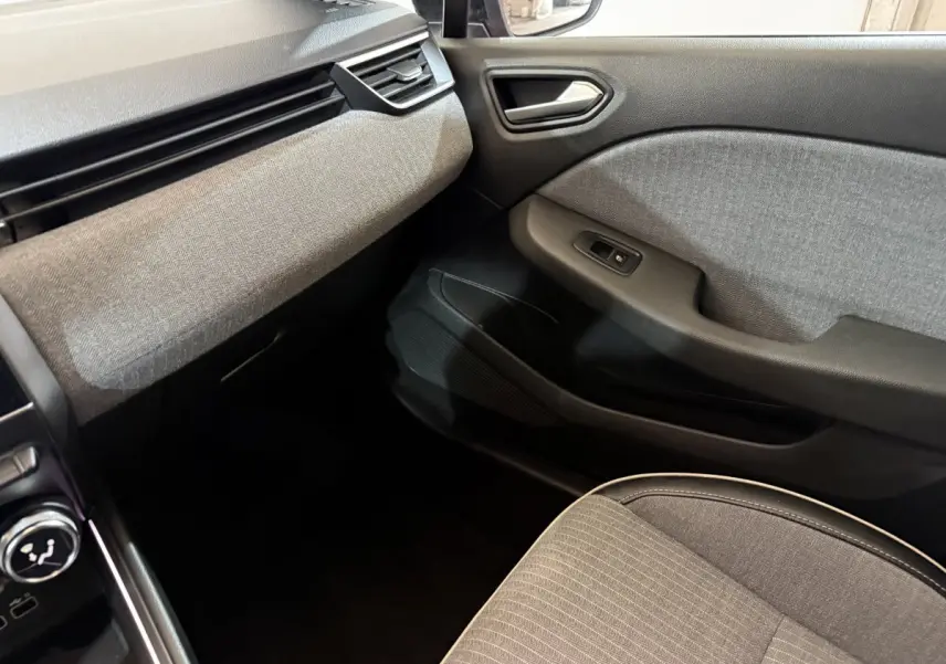 Vue intérieure côté passager de la Renault Clio Techno TCe 90 2024, avec tissu gris et détails noirs sur la porte et siège.