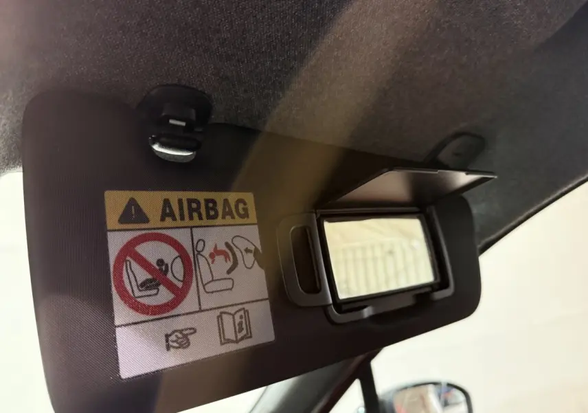 Détail du pare-soleil côté conducteur avec miroir ouvert et avertissement airbag dans une Renault Clio rouge.