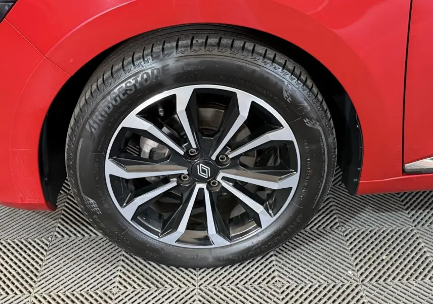 Gros plan sur la roue avant gauche de la Renault Clio Techno TCe 90 rouge, avec jante alliage noire et argentée.