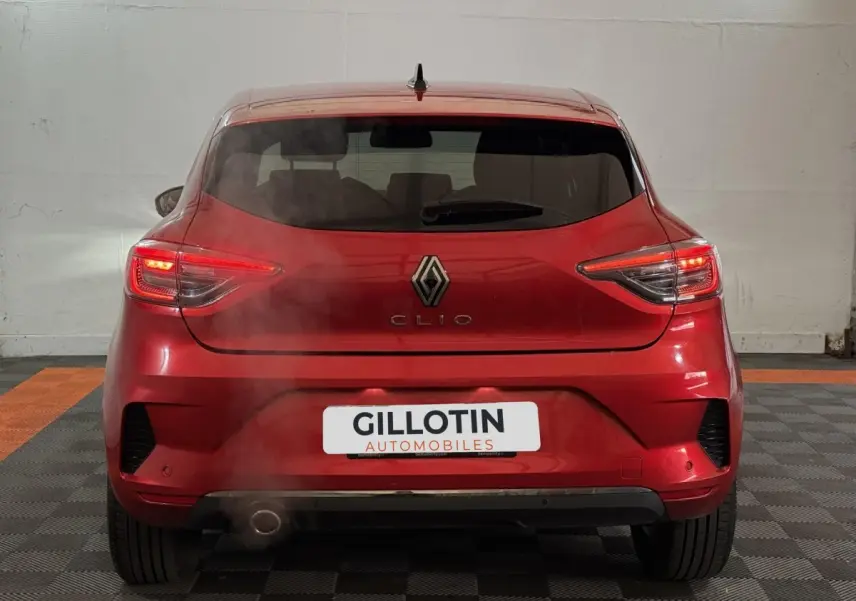 Vue arrière d'une Renault Clio Techno TCe 90 rouge 2024 avec feux LED allumés et fumée visible près de l'échappement.