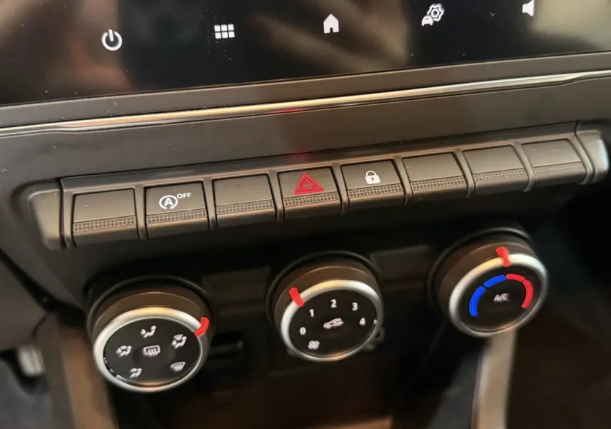 Gros plan sur les commandes de climatisation et boutons de fonction du tableau de bord de la Renault Clio Business blanche.