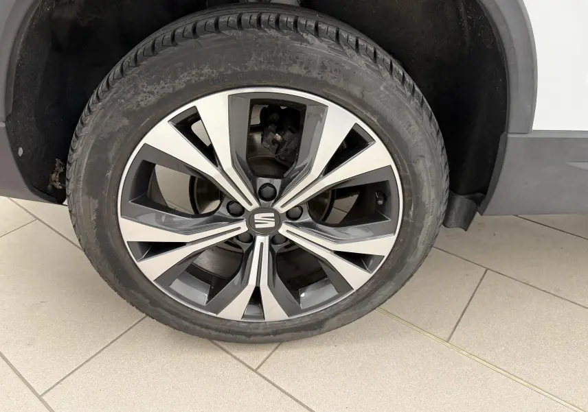 Gros plan sur la roue avant droite du SEAT Ateca blanc Nevada, mettant en valeur la jante alliage bicolore 18 pouces.
