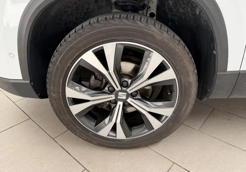 Gros plan sur la roue avant droite du SEAT Ateca blanc Nevada, avec jante alliage bicolore et pneu Bridgestone.