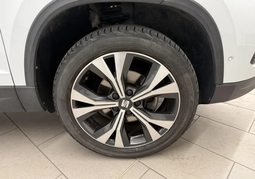 Gros plan sur la roue avant droite du SEAT Ateca blanc Nevada, avec jante alliage bicolore et logo central.