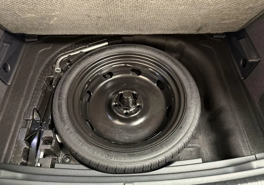 Gros plan sur la roue de secours compacte 18'' noire dans le coffre à double fond du SEAT Ateca Blanc Nevada 2023.