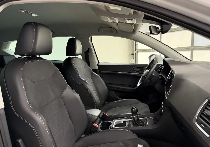 Vue intérieure côté conducteur du SEAT Ateca 2023, sièges noirs en cuir et alcantara avec surpiqûres blanches.