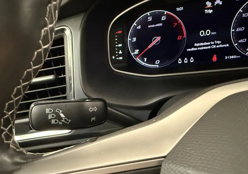 Vue intérieure rapprochée du tableau de bord et du commodo gauche du SEAT Ateca blanc Nevada 2023 avec affichage numérique.