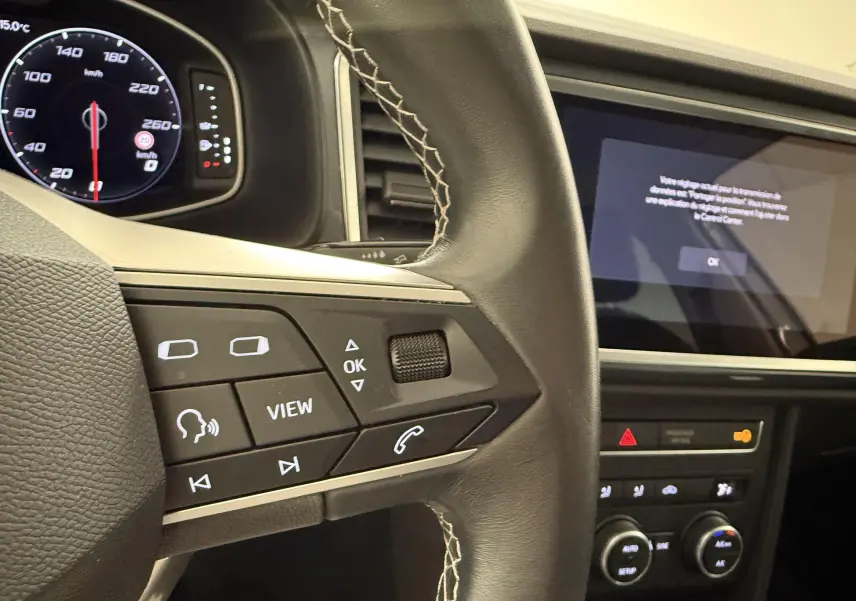 Gros plan sur le volant en cuir noir avec commandes intégrées et tableau de bord digital du SEAT Ateca blanc Nevada 2023.