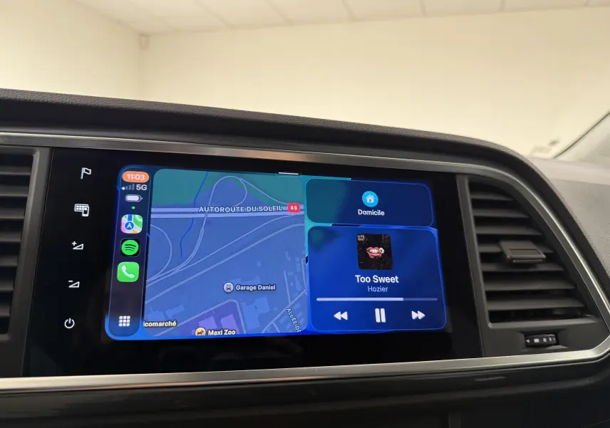 Écran tactile central du tableau de bord du SEAT Ateca blanc Nevada, affichant navigation et musique en cours.