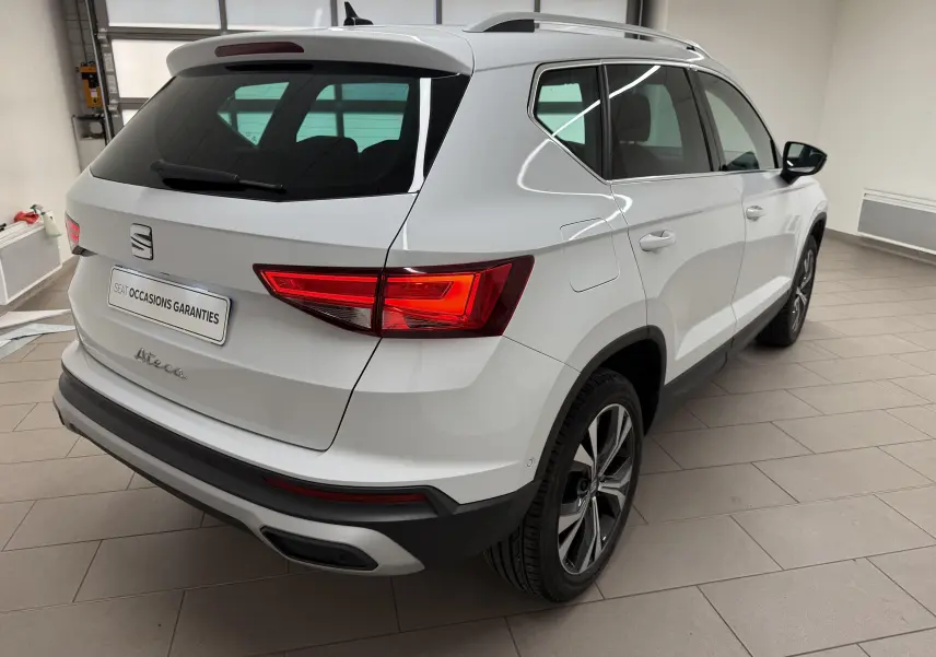 Vue 3/4 arrière droit du SUV SEAT Ateca blanc Nevada 2023 avec feux arrière allumés et jantes alliage distinctives.