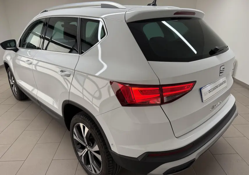 Vue 3/4 arrière droite du SEAT Ateca blanc Nevada 2023 avec feux arrière allumés et jantes alliage bicolores.