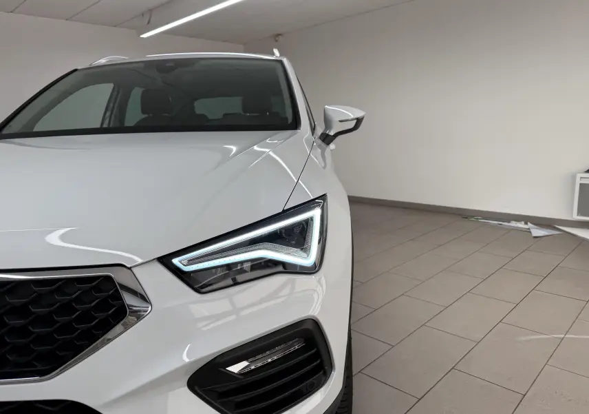Vue avant droite rapprochée du SEAT Ateca blanc Nevada 2023, mettant en valeur son phare LED au design anguleux.