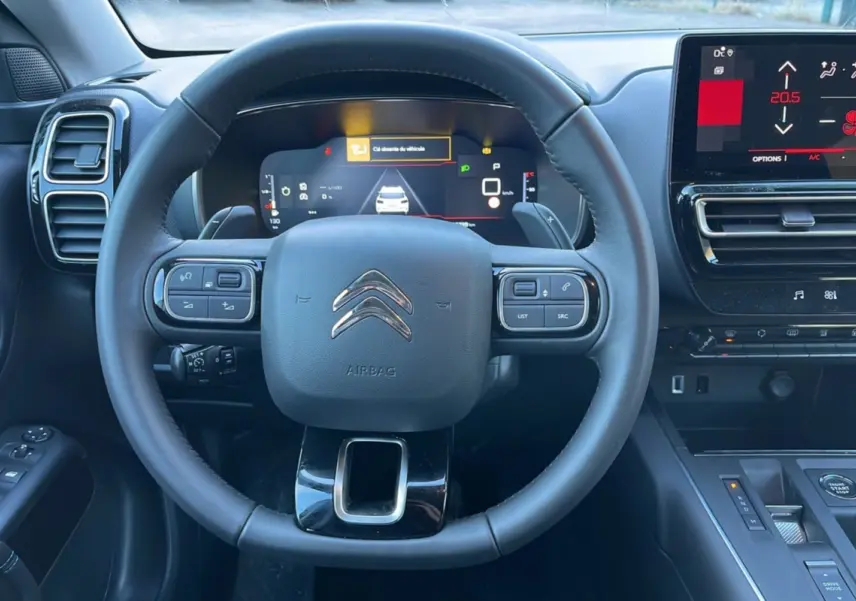 Vue centrée sur le volant cuir multifonctions et le tableau de bord numérique du Citroën C5 Aircross Hybrid blanc.