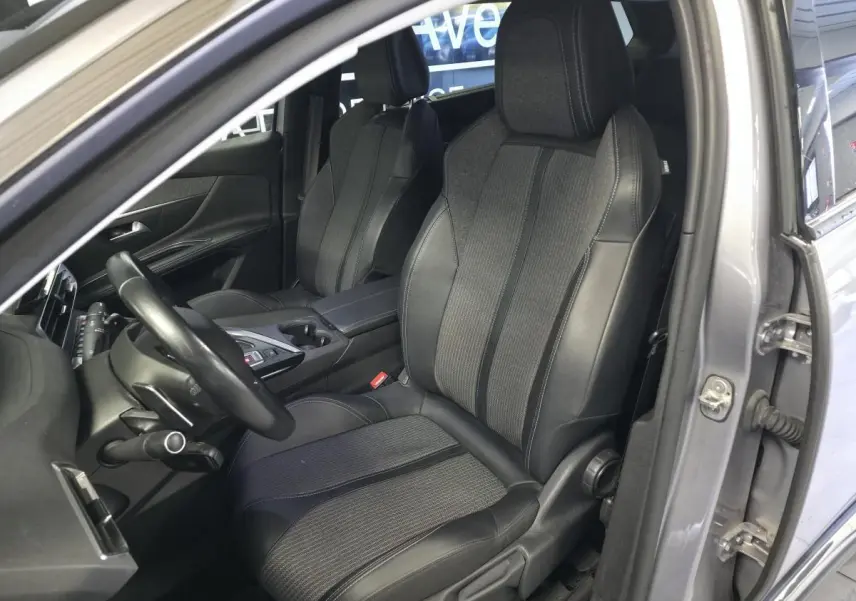 Vue intérieure côté conducteur du Peugeot 5008 gris 2022, mettant en valeur les sièges TEP & tissu et le volant cuir.