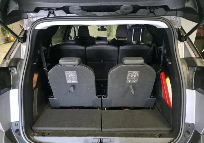Vue arrière du coffre ouvert d’un Peugeot 5008 gris, montrant les sièges escamotés du troisième rang et l’habitacle noir.