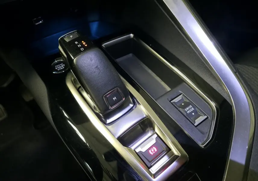 Gros plan sur la console centrale noire du Peugeot 5008 2022, avec levier de boîte auto et bouton Drive Mode.