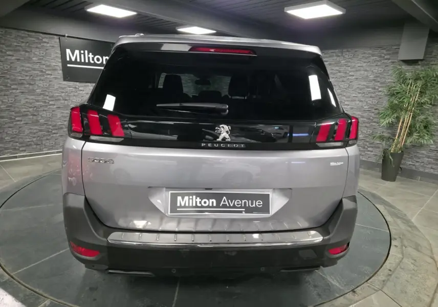 Vue arrière d'un Peugeot 5008 gris métallisé avec feux arrière à griffes rouges et logo lion central.