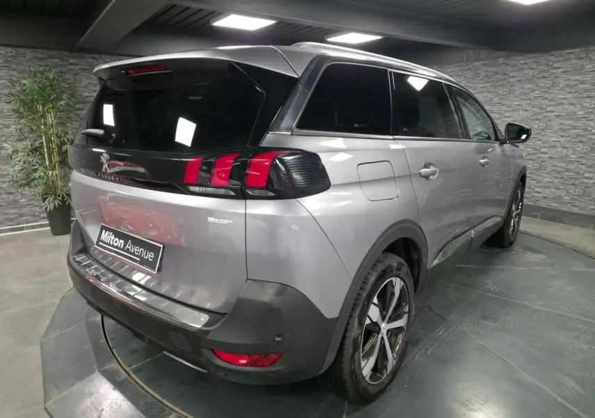 Vue 3/4 arrière droite du Peugeot 5008 gris métallisé avec vitres surteintées et jantes alliage bi-ton.