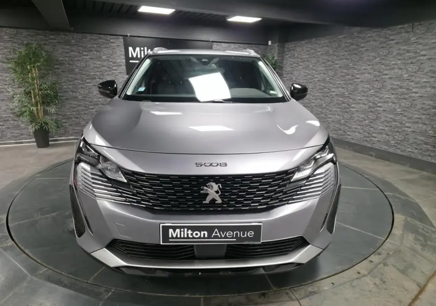 Peugeot 5008 gris métallisé vue de face, calandre à damier chromé et phares LED distinctifs.