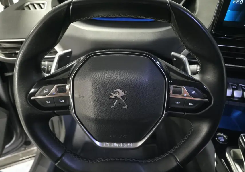 Volant compact en cuir noir du Peugeot 5008 2022, vue frontale centrée sur les commandes multifonctions et le logo lion.