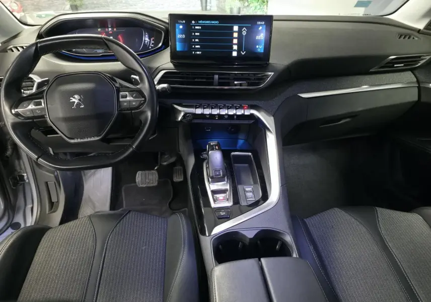 Vue intérieure avant du Peugeot 5008 gris, montrant le volant compact, l'écran tactile 10 pouces et la console centrale moderne.