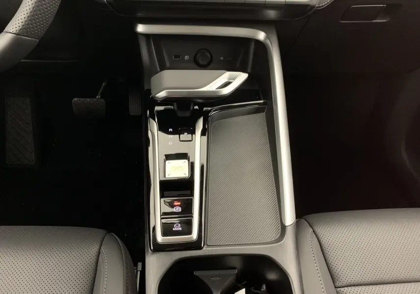 Vue plongeante sur la console centrale noire brillante du MG ZS 1.5 L Hybrid+ avec levier de vitesses et bouton start/stop.
