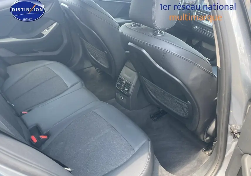Vue intérieure arrière côté droit de la BMW Série 1 gris foncé, montrant les sièges en tissu et similicuir avec rangements au dos des sièges avant.