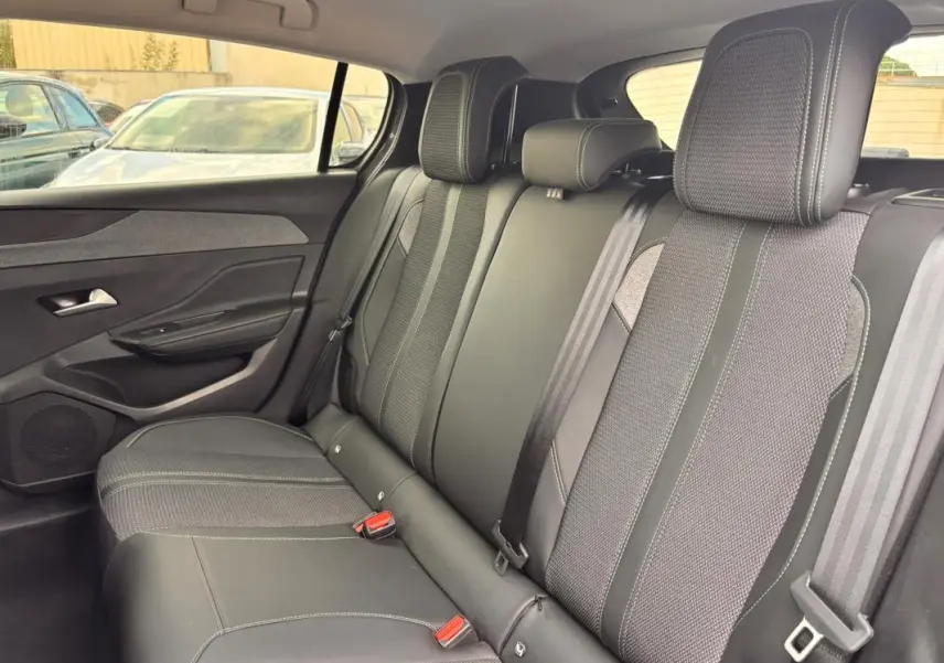 Vue latérale intérieure des sièges arrière gris du Peugeot 308 Hybrid 145 e-DCS6 Allure avec ceintures et appuie-têtes visibles.