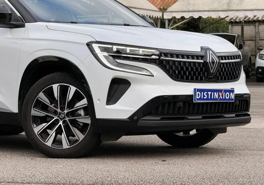 Vue 3/4 avant gauche du Renault Austral E-Tech blanc nacré avec toit noir, mettant en valeur sa calandre et ses jantes bicolores.
