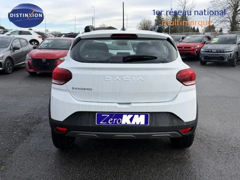 Vue arrière d'une Dacia Sandero blanche Glacier 2025, version 1.0 TCe 90ch Expression, sur un parking multimarque.