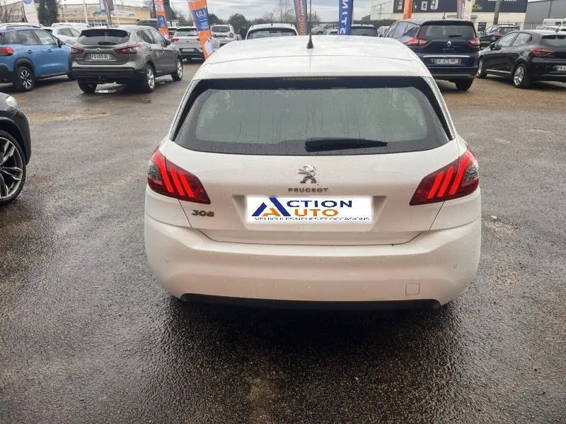 Vue arrière d'une Peugeot 308 blanche Banquise avec feux arrière LED et lunette arrière teintée sur parking.