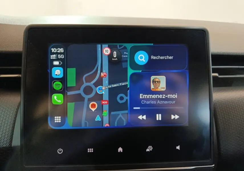 Écran tactile central de la Renault Clio gris clair 2023 affichant navigation et musique en cours de lecture.
