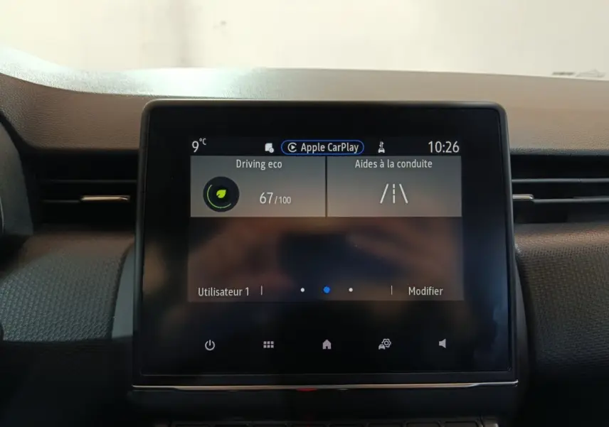 Écran tactile central de la Renault Clio gris clair 2023 affichant Apple CarPlay et aides à la conduite.