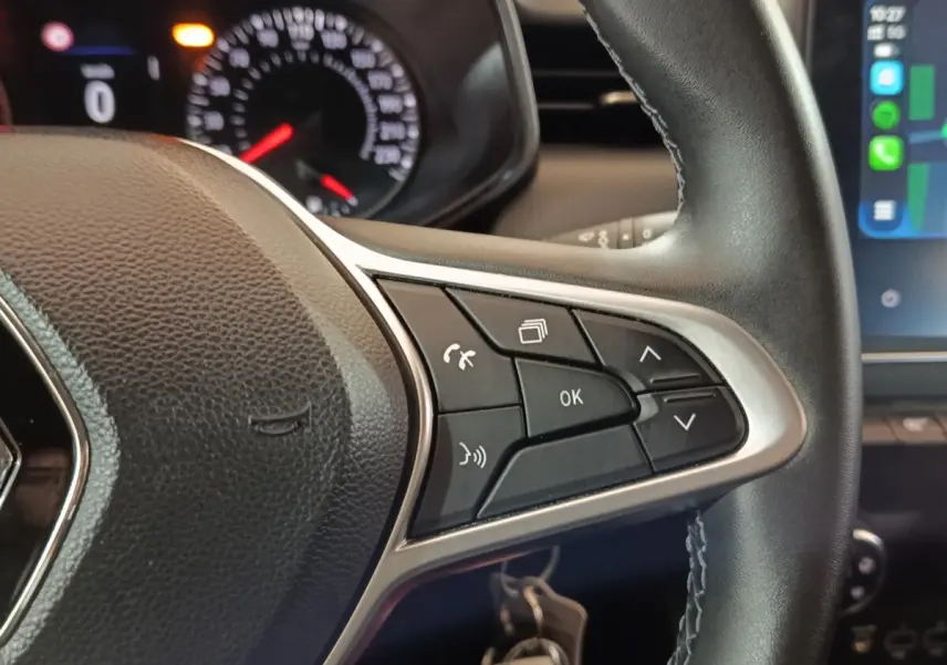 Gros plan sur le volant cuir synthétique noir de la Renault Clio 2023 avec commandes multifonctions et tableau de bord partiel.