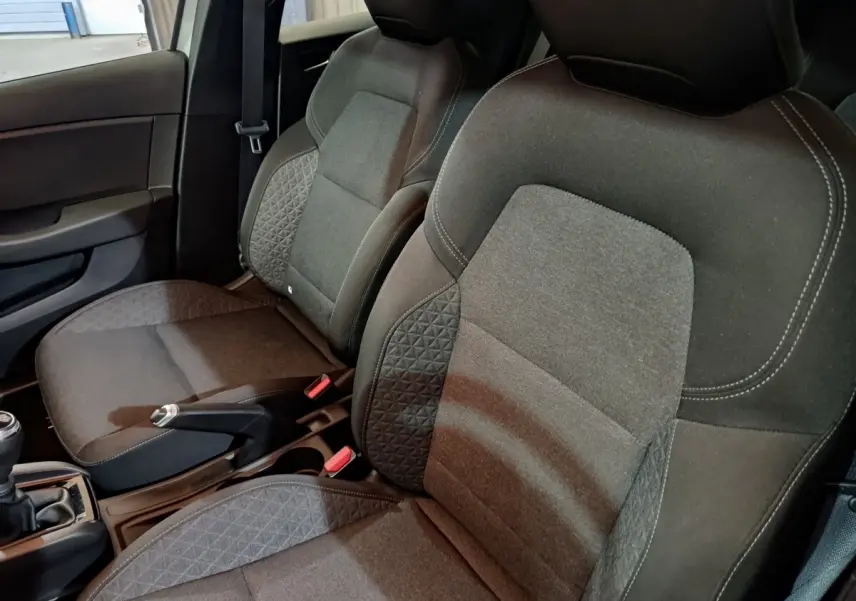 Vue rapprochée des sièges avant gris foncé de la Renault Clio Equilibre TCe 90, avec console centrale et frein à main visible.