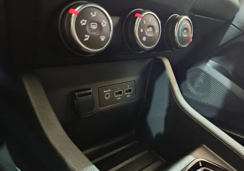 Gros plan sur les commandes de climatisation et les ports USB/Aux-In du tableau de bord de la Renault Clio gris clair 2023.