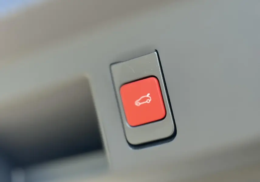 Bouton rouge d'ouverture électrique du hayon sur un véhicule Citroën C5 Aircross blanc, vue en gros plan.